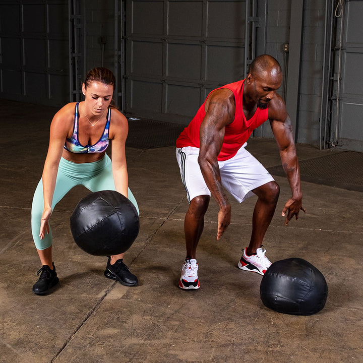 Two athletes performing partner exercises using Body-Solid soft medicine balls.