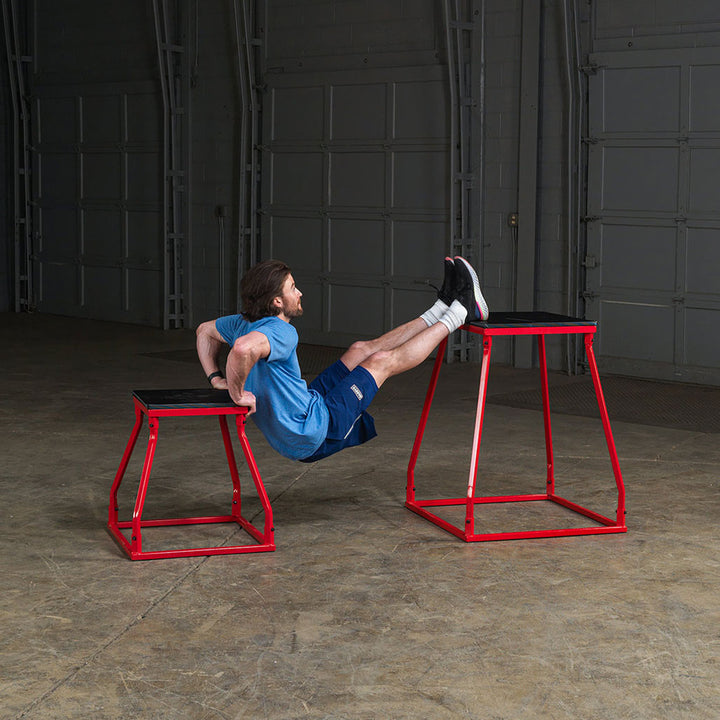Athlete performing a core exercise between two steel frame plyo boxes.