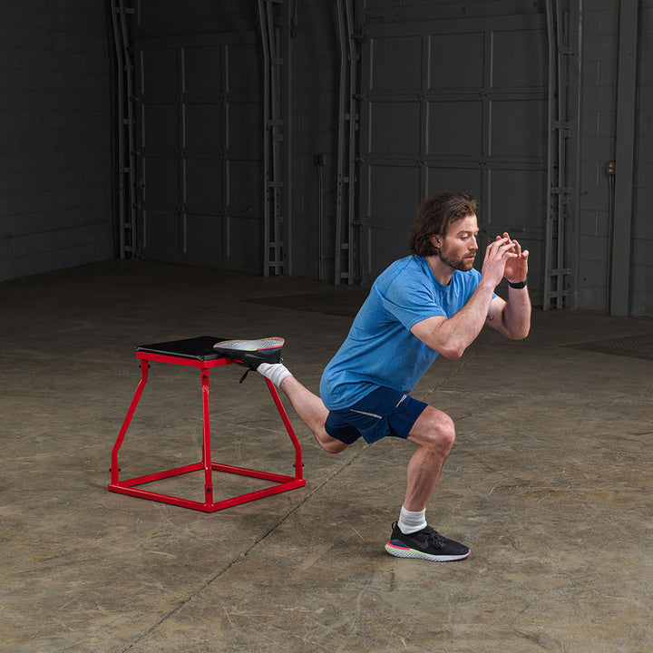 Athlete performing squat exercises using a steel frame plyo box.