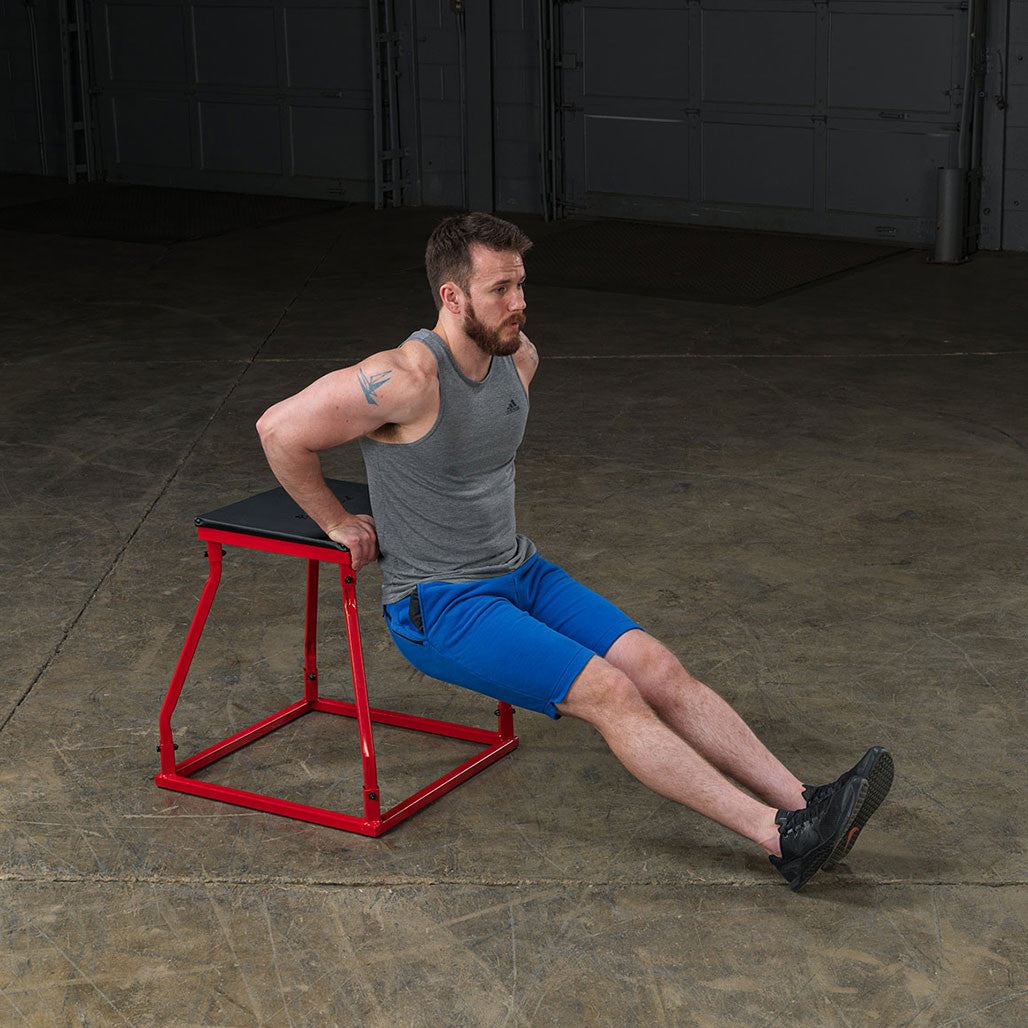 Athlete performing tricep dips using a steel frame plyo box.