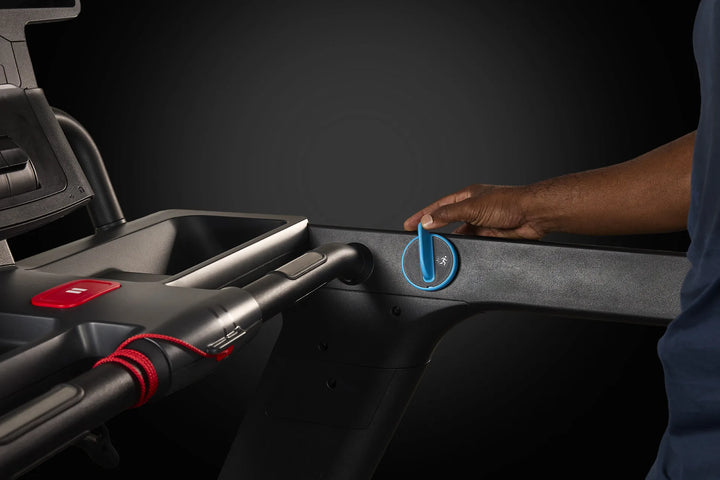 Hand adjusting the speed and incline control dial on the Precor Breakaway treadmill.