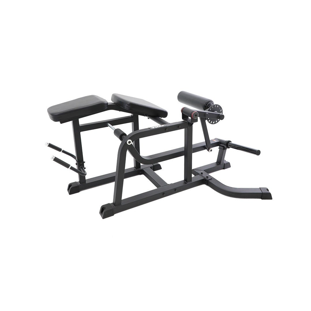 Side view of prone leg curl machine showing bench and leg roller assembly.