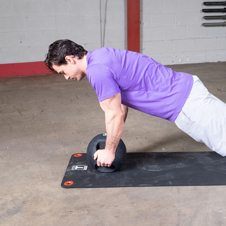 Athlete performing a push-up exercise using a Body-Solid dual grip medicine ball.