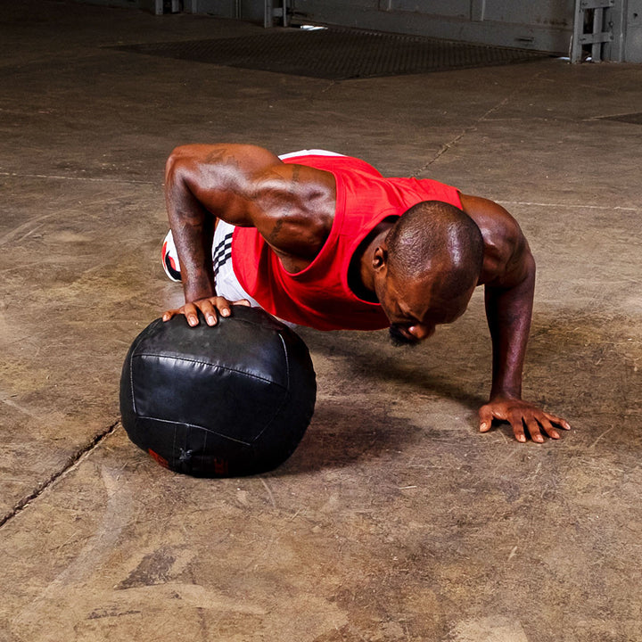Athlete performing a push-up using a Body-Solid Premium Dynamax soft medicine ball.