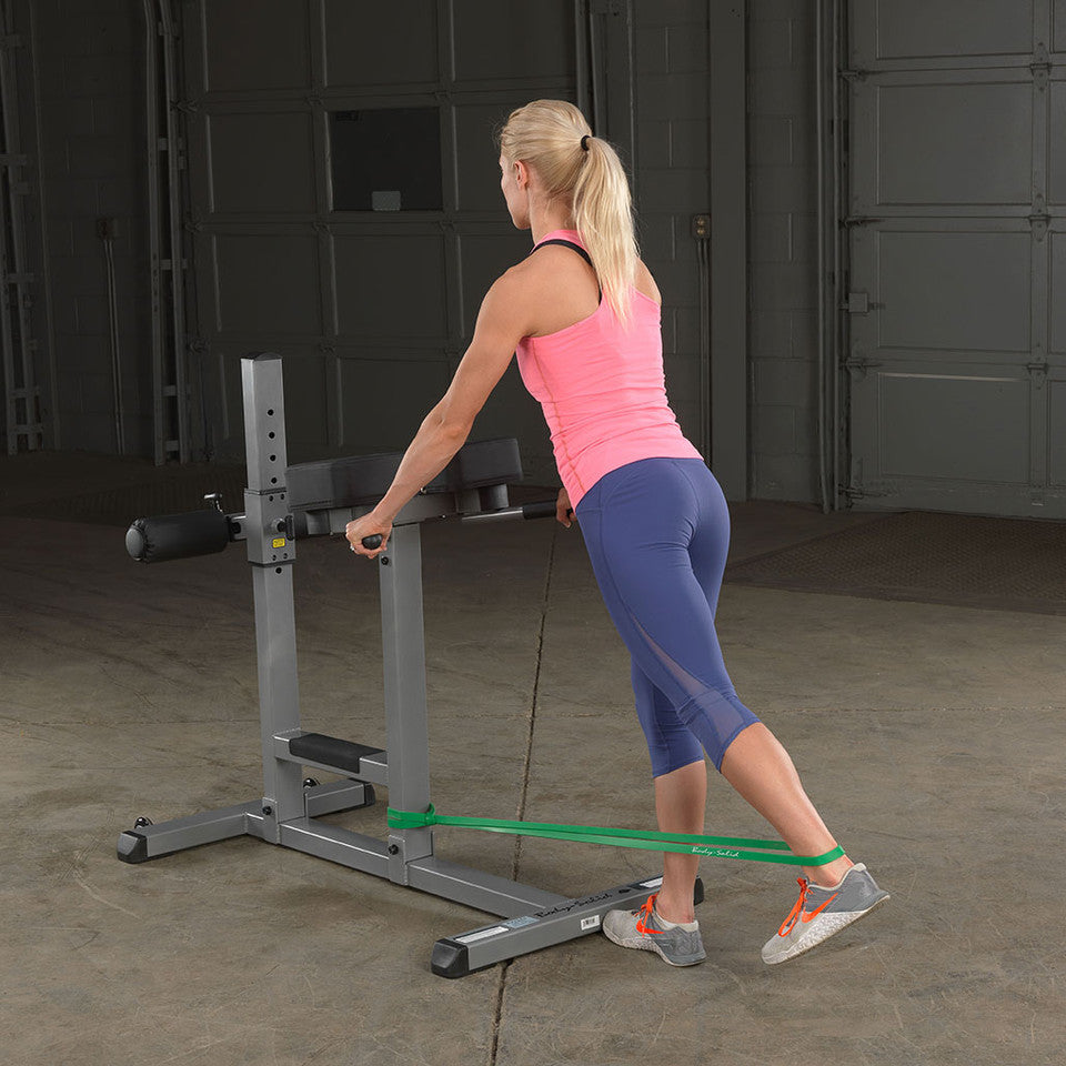 User performing a standing leg kickback exercise with a Body-Solid resistance loop band.