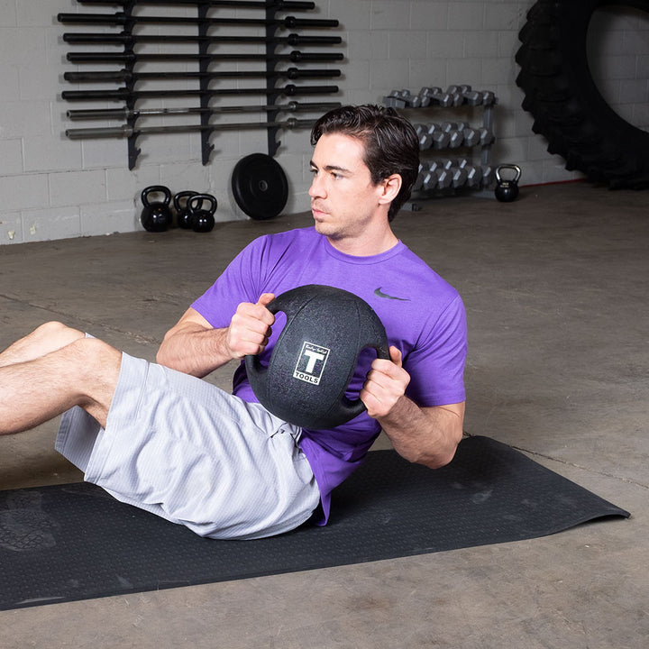 Person performing a seated rotational exercise with a Body-Solid dual grip medicine ball.