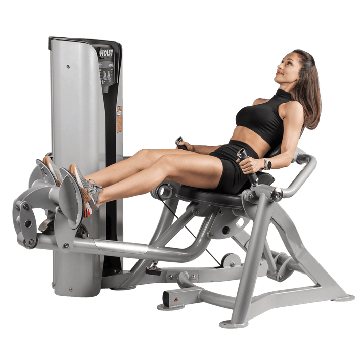 woman seated on mid row machine with legs extended and arms forward preparing to perform rowing exercise