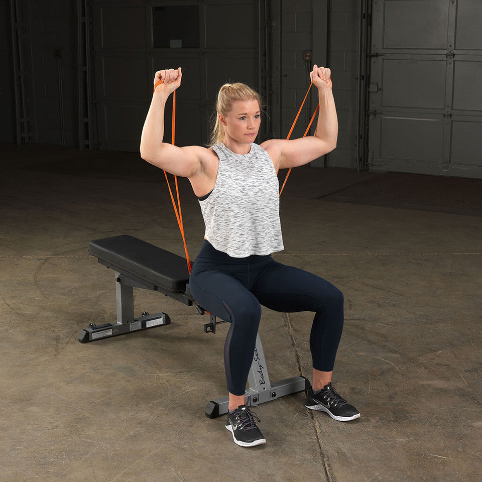 User performing a seated shoulder press using a Body-Solid resistance loop band.