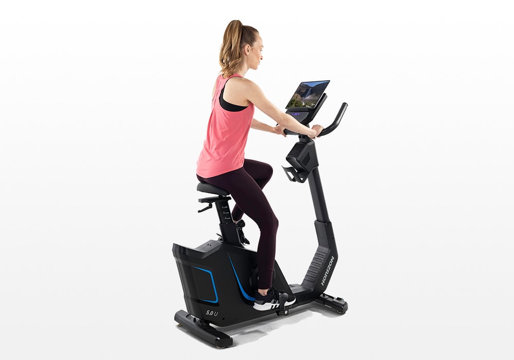 User riding the Horizon 5.0U upright exercise bike from the side.