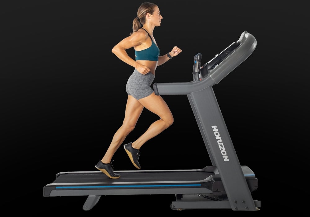 Side view of a person running on the Horizon 7.4 AT treadmill.