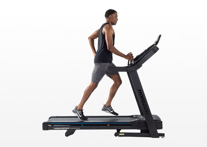 Side view of a person walking on the Horizon 7.0 AT treadmill.
