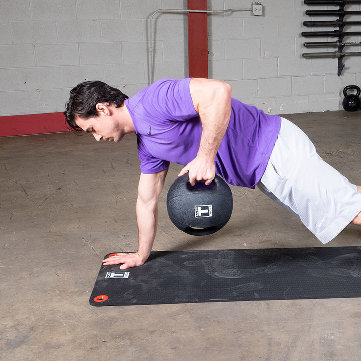 Athlete using a Body-Solid dual grip medicine ball during a single-arm floor exercise.