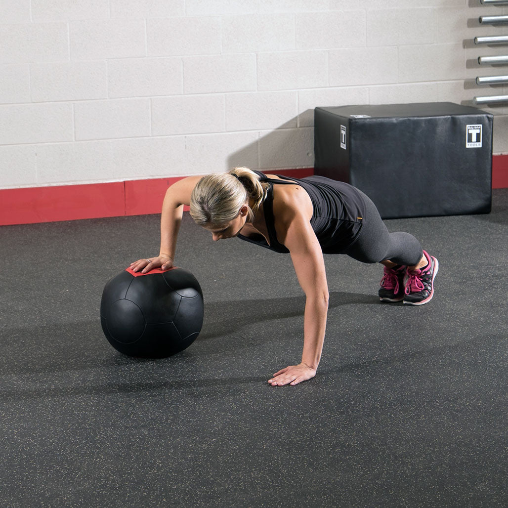 Athlete using a Body-Solid soft shell medicine ball during a floor-based training exercise