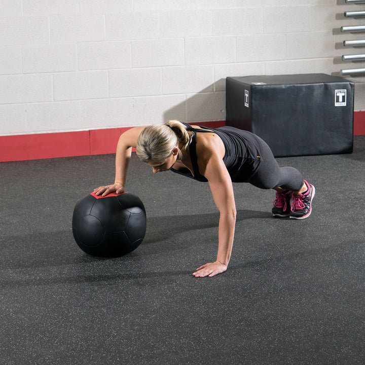 Athlete using a Body-Solid soft shell medicine ball during a floor-based training exercise
