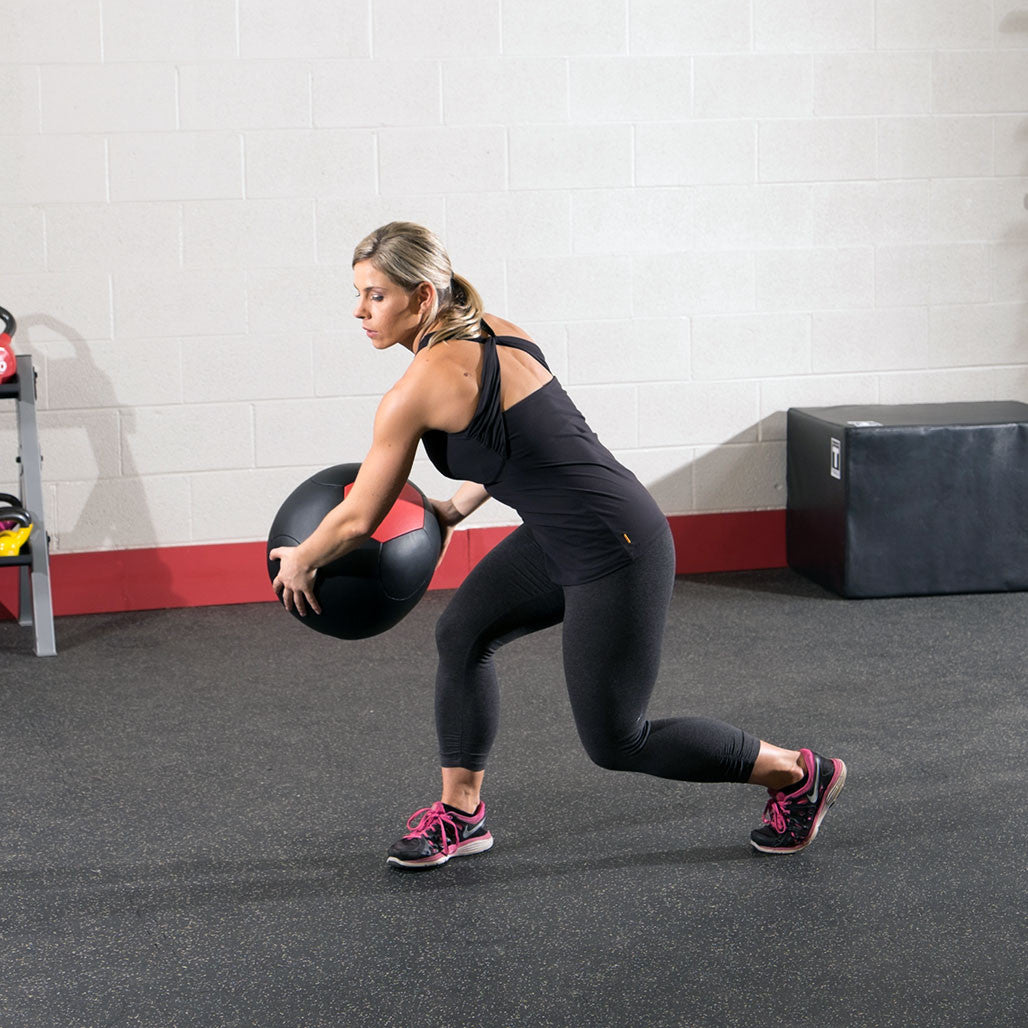 Athlete performing a lunge while holding a Body-Solid soft shell medicine ball