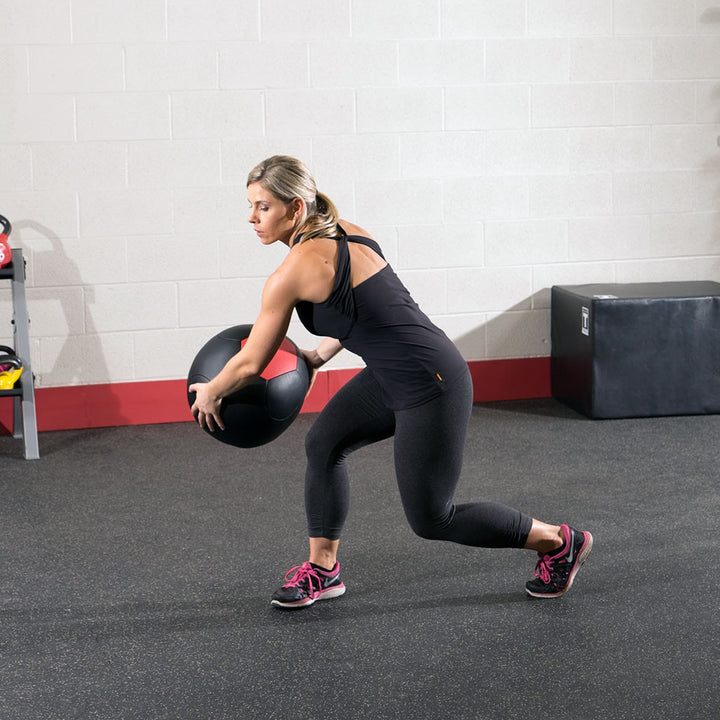 Athlete performing a lunge while holding a Body-Solid soft shell medicine ball