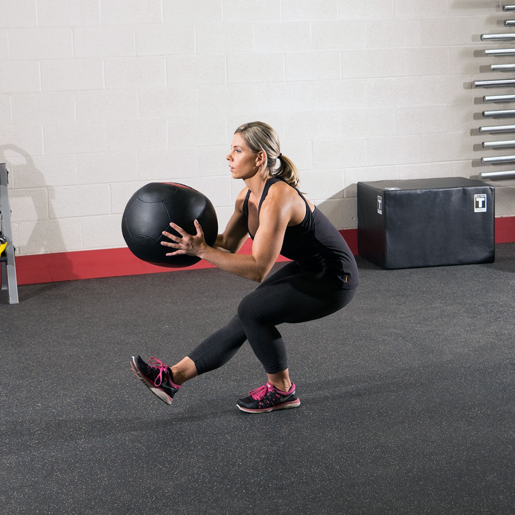 Athlete holding a Body-Solid soft shell medicine ball during a single-leg training exercise