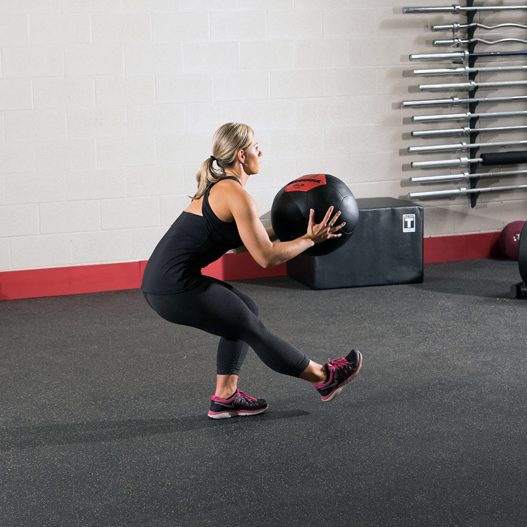 Athlete performing a squat while holding a Body-Solid soft shell medicine ball