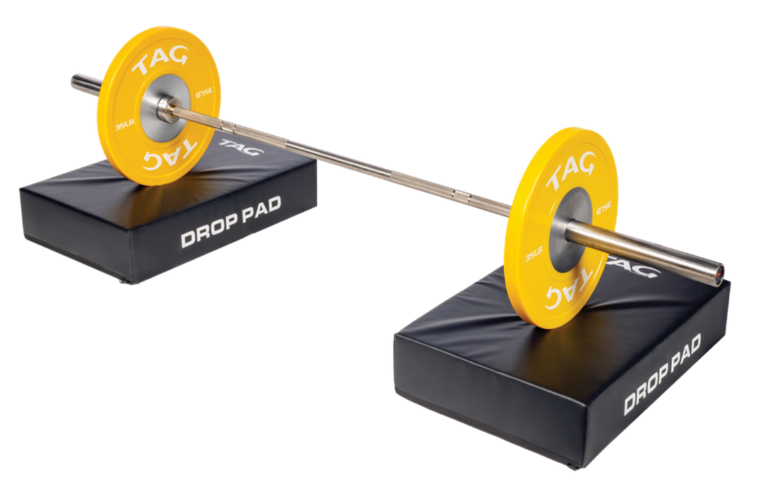 Pair of TAG barbell drop pads positioned under a loaded barbell for barbell training