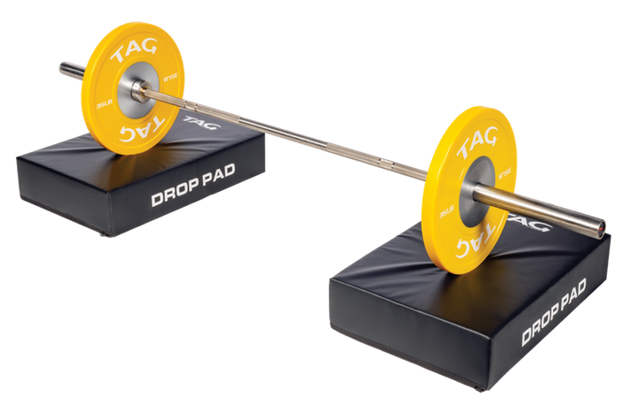 Pair of TAG barbell drop pads positioned under a loaded barbell for barbell training