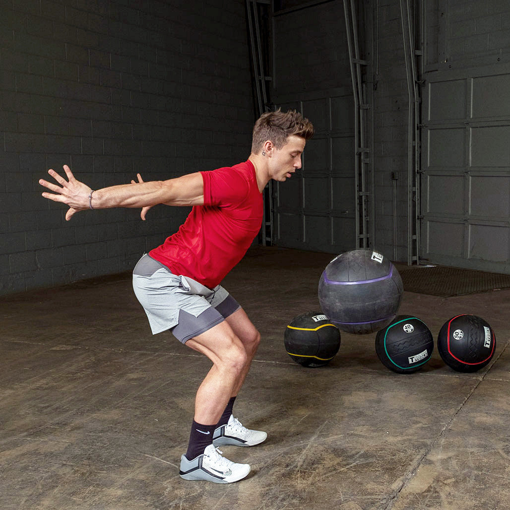 Athlete performing a wall ball exercise with a heavy rubber medicine ball.