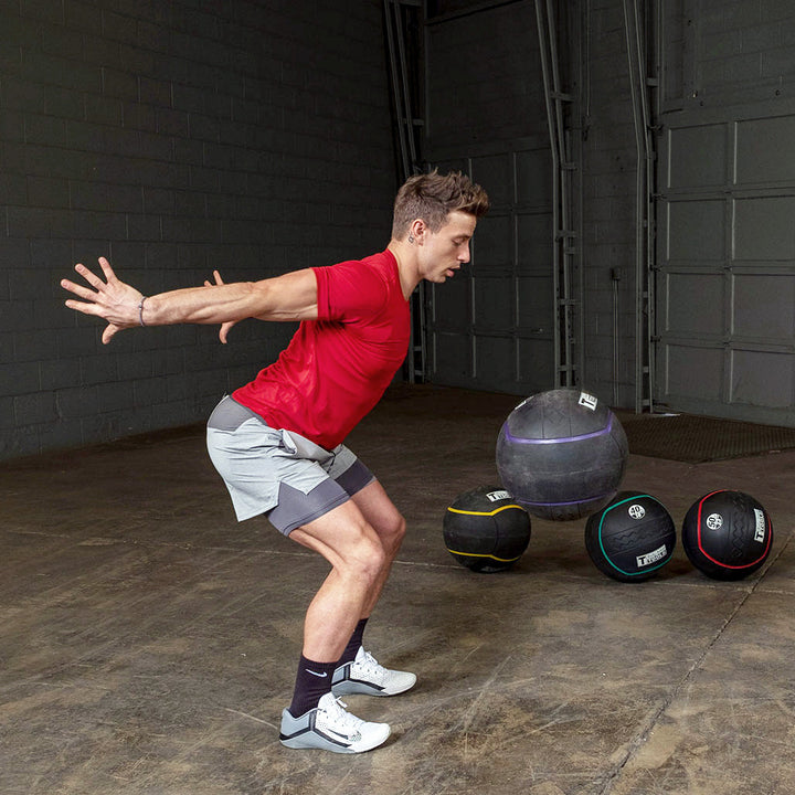 Athlete performing a wall ball exercise with a heavy rubber medicine ball.