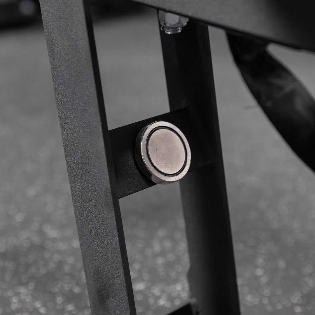 Close-up of the black Torque USA X-CREATE belt squat attachment showing the magnetic latch on its folding kickstand.