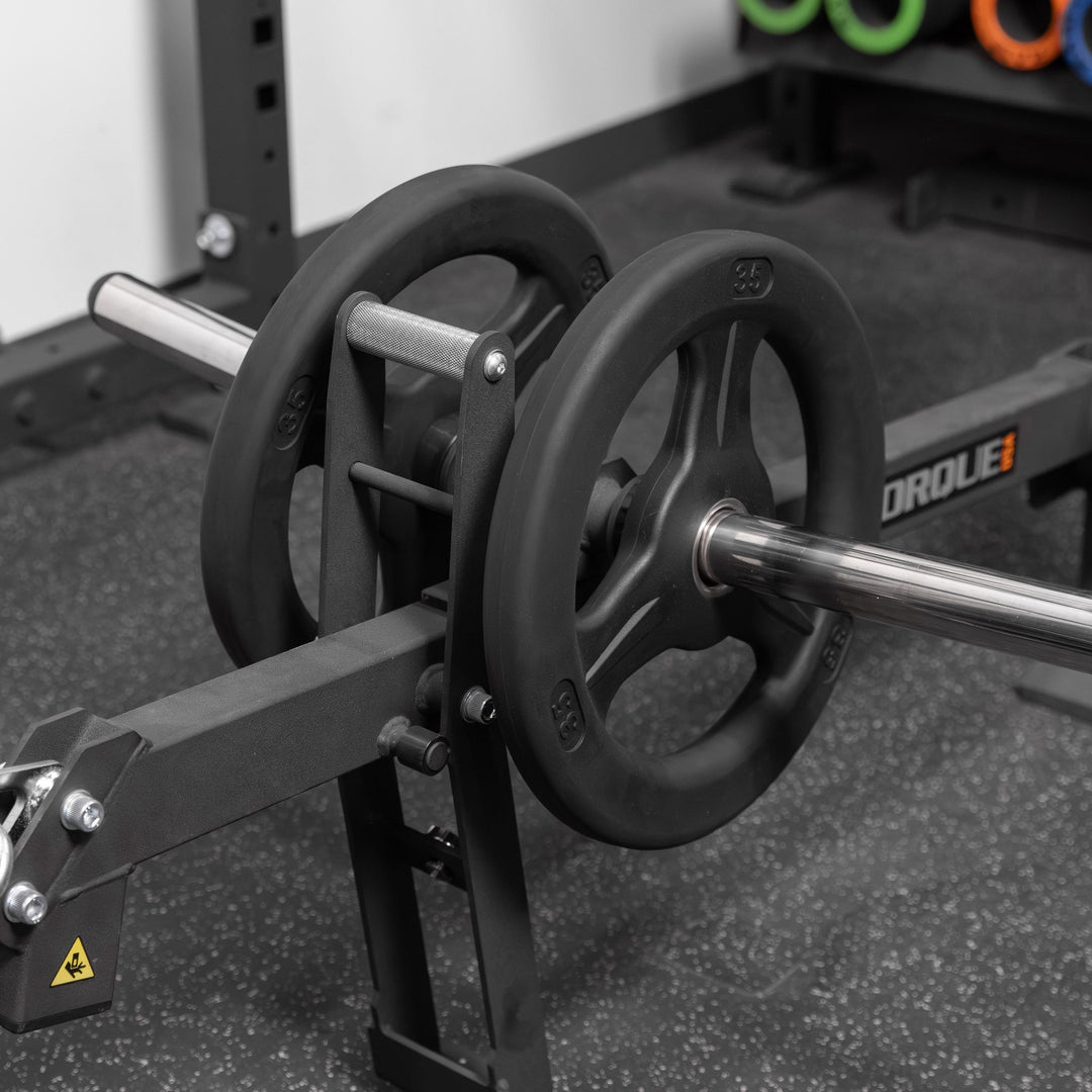 Close-up of Torque USA X-CREATE black belt squat attachment with weight plates loaded onto the silver weight horn.