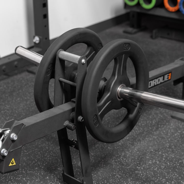 Close-up of Torque USA X-CREATE black belt squat attachment with weight plates loaded onto the silver weight horn.