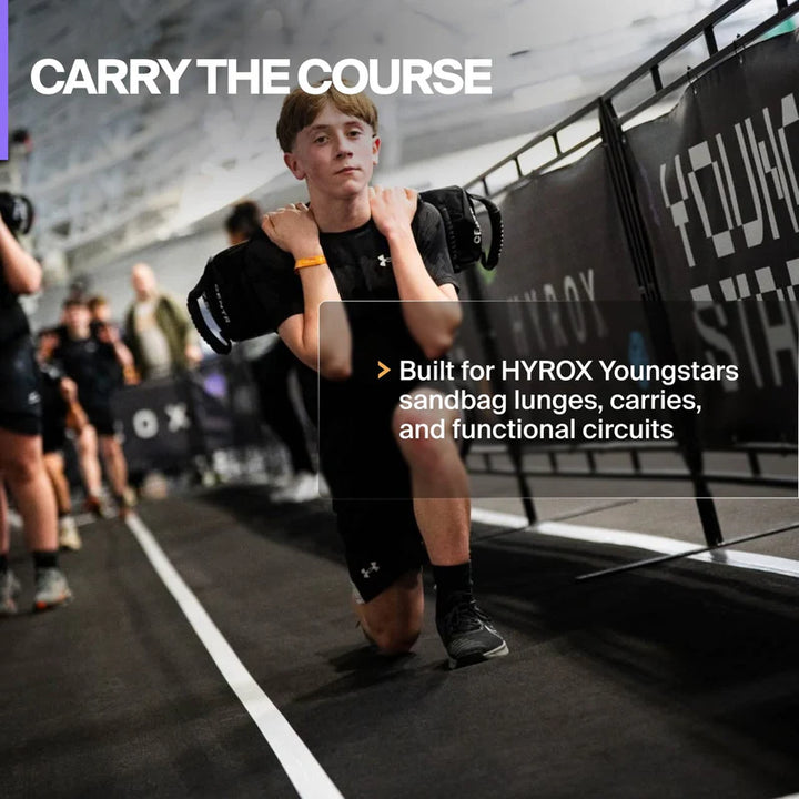 Young athlete carrying the Centr x HYROX competition sandbag during functional training.