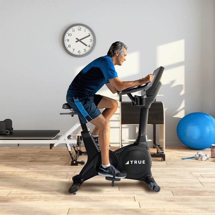 Person exercising on a TRUE Fitness upright bike in a home gym