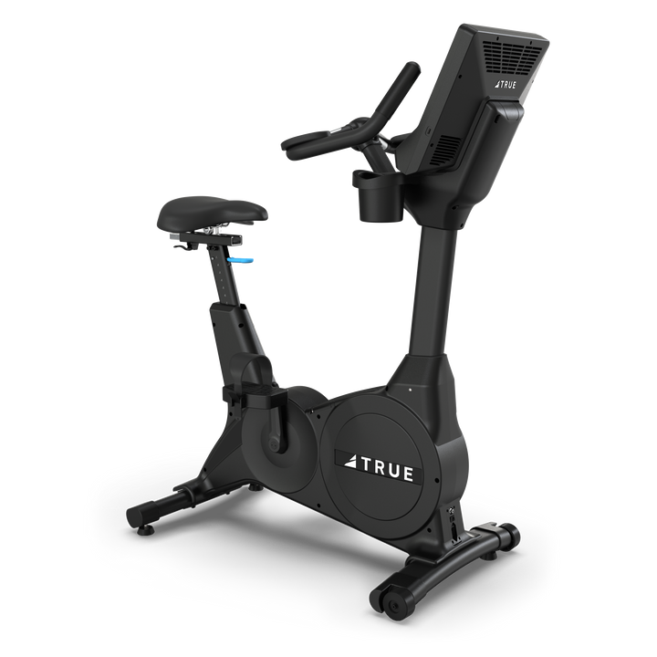 TRUE Fitness upright exercise bike with console and adjustable seat, side view